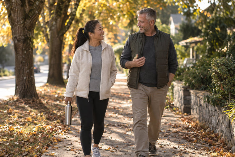 A couple walking a tree-lined path in the morning, one carrying a water bottle