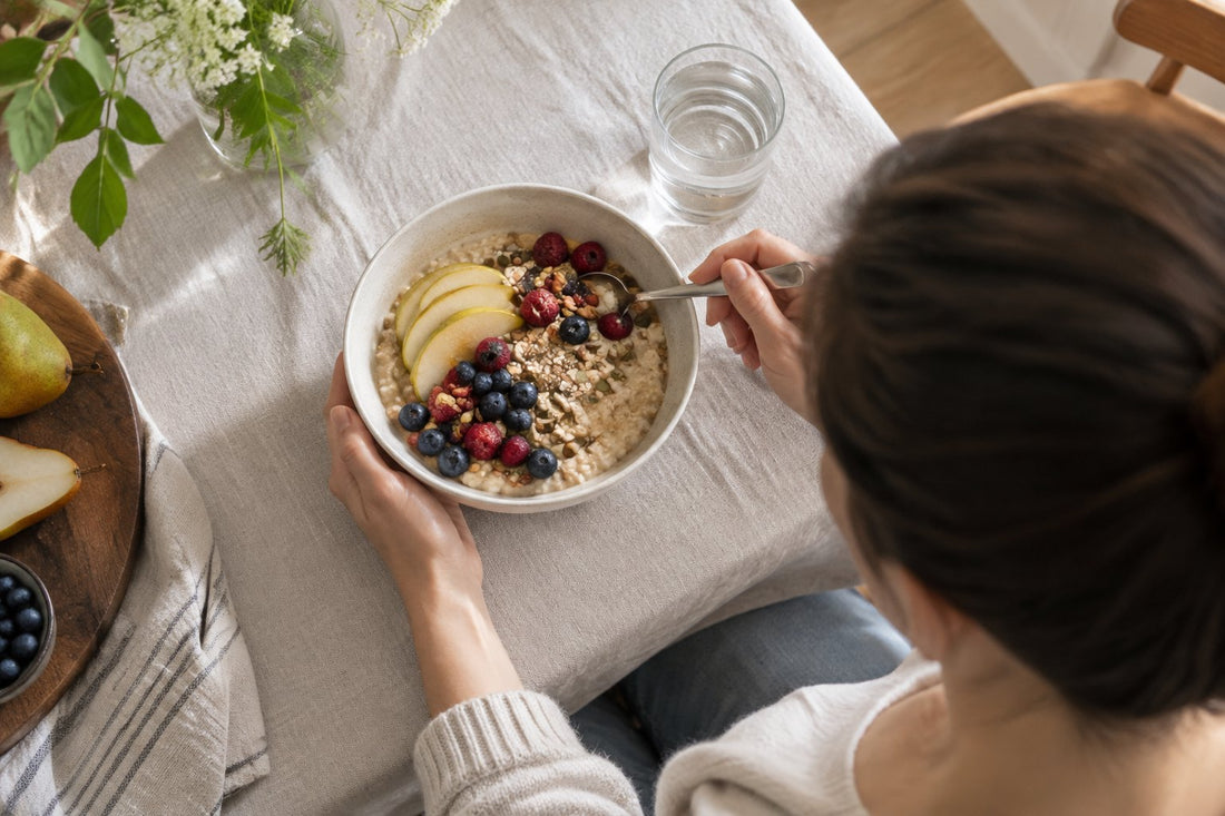 A breakfast bowl of oats with berries and pear beside a glass of water