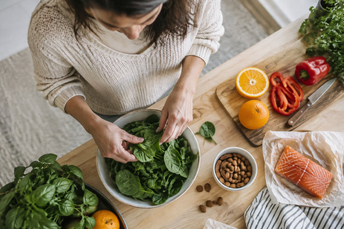 Fresh vegetables, citrus, almonds and salmon arranged on a wooden counter