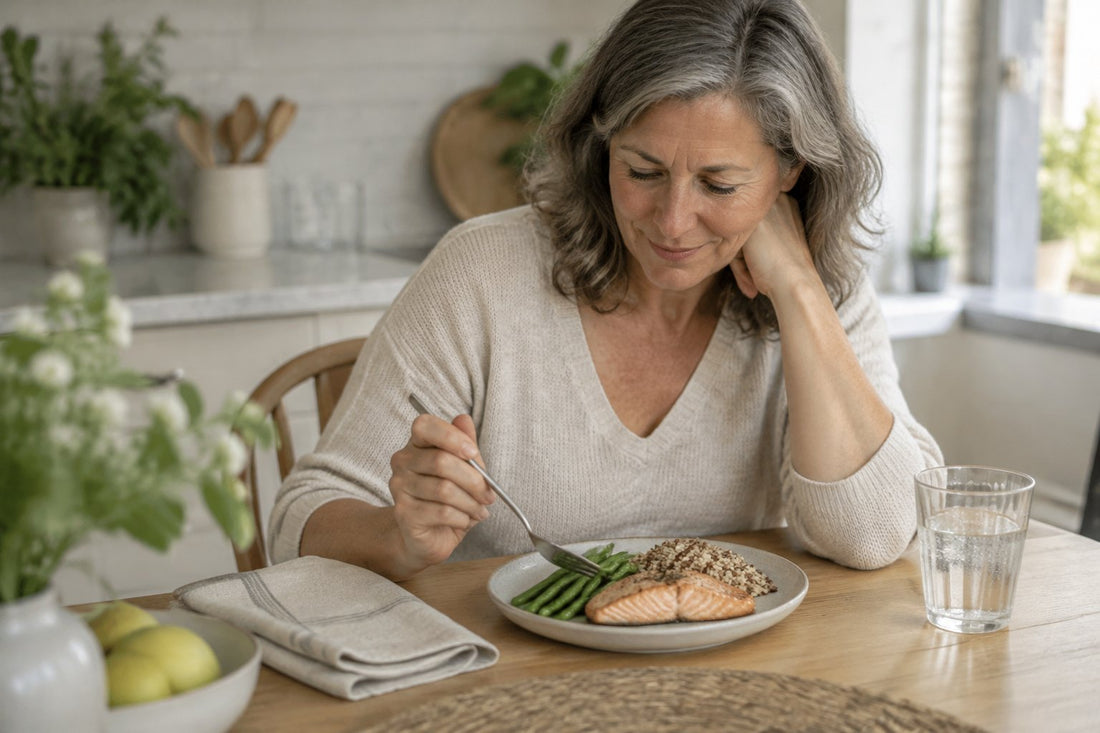 A woman at a kitchen table looking at a small plate of simple food